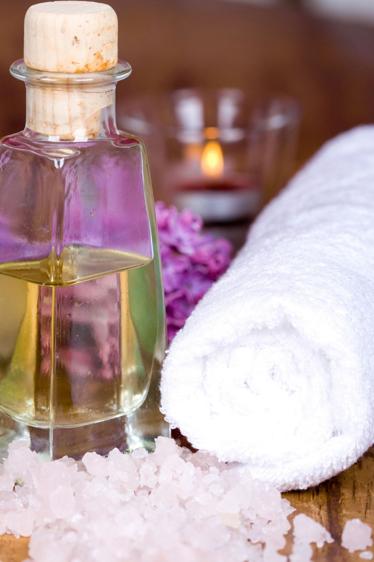 Rolled towel, massage oil and fresh lilac prepared for a relaxation massage